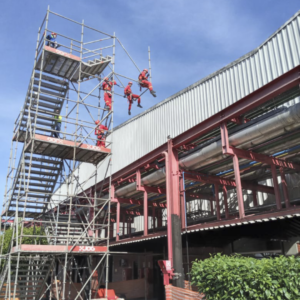 Montadores de andaime finalizando uma plataforma de acesso ao telhado.